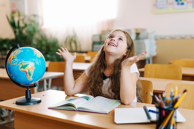 Free photo schoolgirl at desk looking up