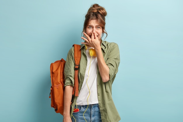 Schoolgirl experiencs stench or bad smell while going to college, covers nose and has displeased facial expressioon