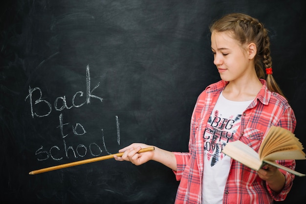 Schoolgirl holding book and pointer standing