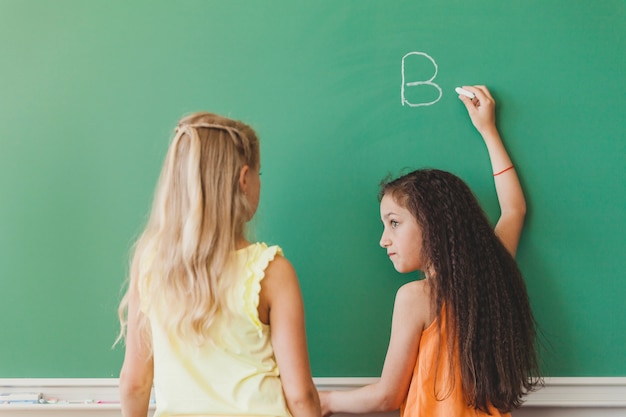 Free photo schoolgirl holding chalk looking away