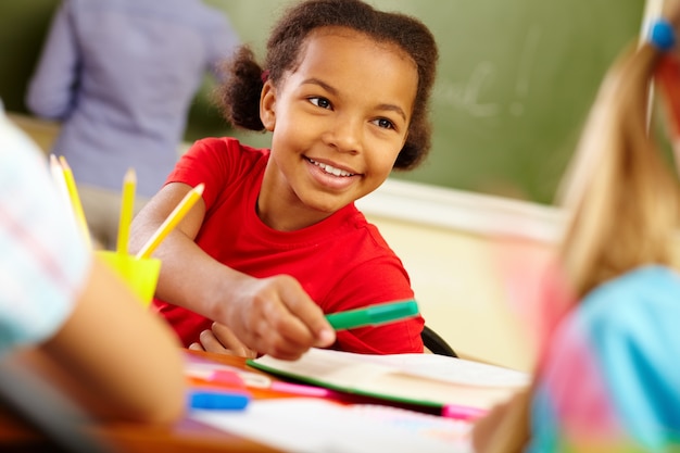 Schoolgirl sitting in class and holding a green marker