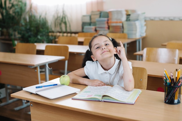 Free photo schoolgirl sitting and pointing up