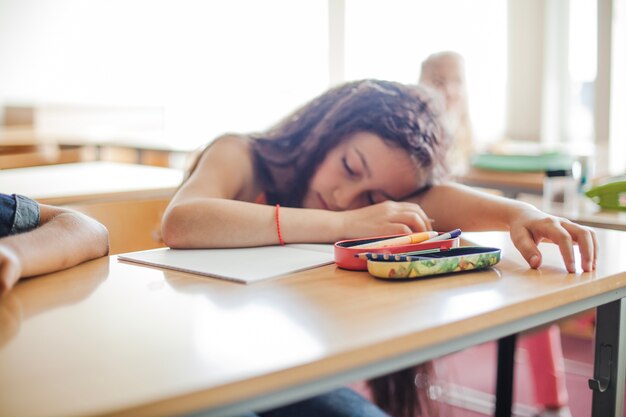 Schoolgirl sitting at table sleeping