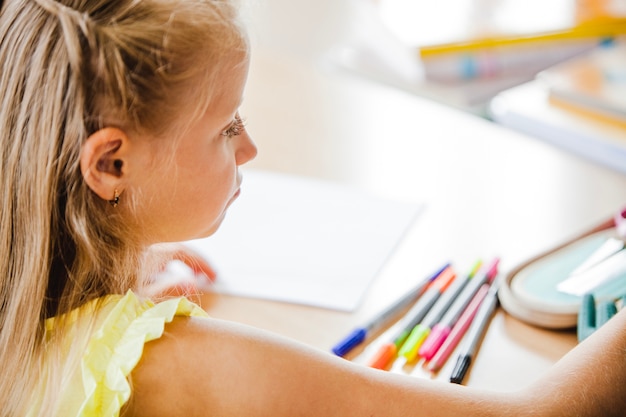 Free photo schoolgirl sitting at table with notebook