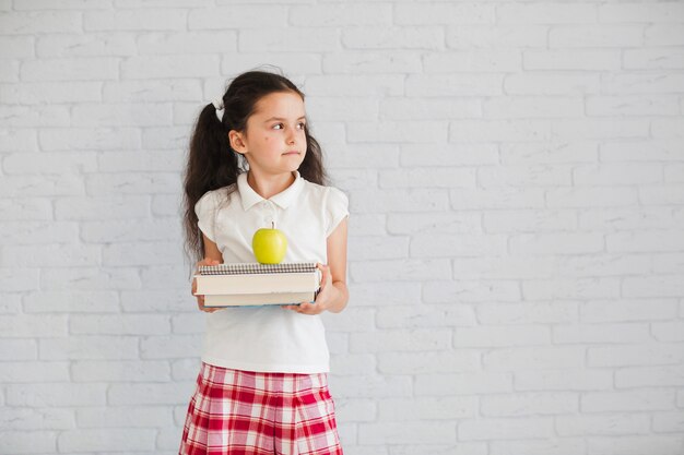 Schoolgirl standing holding books apple