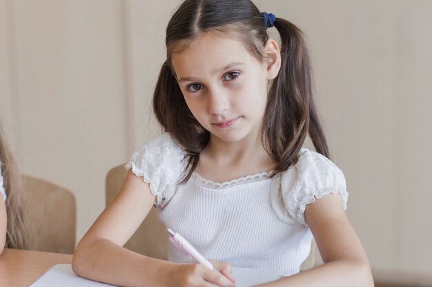 Schoolgirl in white blouse looking at camera