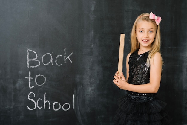 Free photo schoolgirl with ruler at blackboard