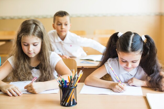 Schoolgirls sitting at table writing