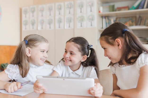 Schoolgirls with tablet looking at each other