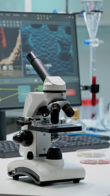 Scientific microscope on laboratory desk with researching instruments