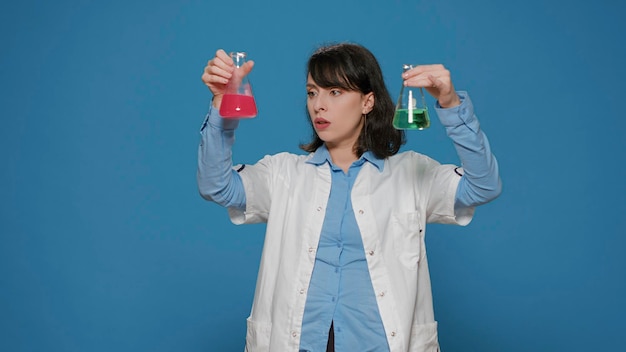 과학 전문가는 실험 분석을 위해 화학 항아리에 있는 물질 샘플을 사용하여 유리 비커에서 액체 공식을 분석합니다. 스튜디오에 DNA가 있는 플라스크를 들고 있는 여성 생화학자.