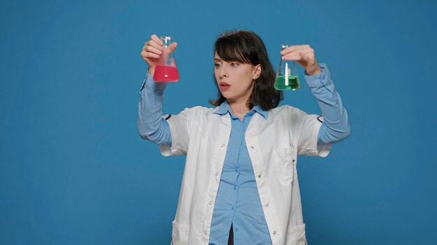 Scientific specialist analyzing liquid formula in glass beaker, using substance sample in chemistry jar for experiment analysis. Female biochemist holding flask with dna in studio.