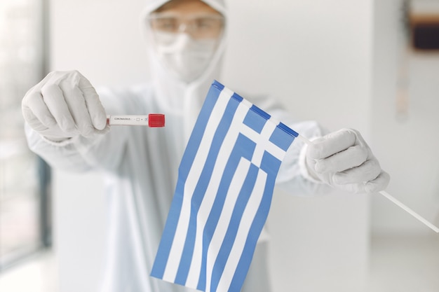 The scientist in coverall suit with a coronavirus sample and Greek flag