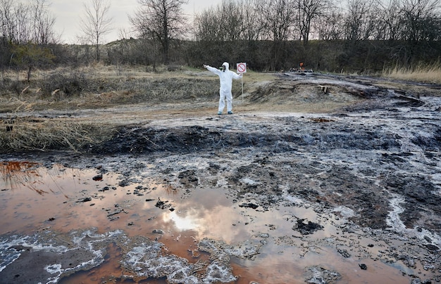 Ученый исследует территорию выброса загрязненного водного человека в защитном костюме