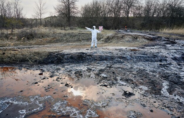 領土排出地域を調査している科学者は、防護服を着て水質汚染された水人を汚染しました