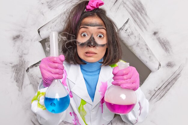  scientist holds liquid substance in flasks with steam works in scientific chemical laboratory wears white coat breaks through paper 