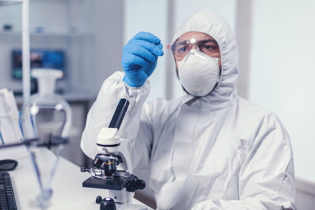 Free photo scientist looking at a microscope slide dressed in coverall during coronavirus