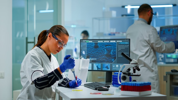 マイクロピペットで創薬を検査する近代的な設備の整った医療研究所の科学者。ハイテクと技術研究治療を使用してワクチンの進化を調べる医療関係者、開発者