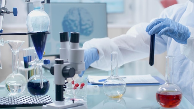 과학자 연구원 화학자 의사는 병원 실험실에서 미생물학 실험을 하는 동안 투명한 유리 제품 혼합 액체 용액을 사용합니다. 테이블에 의료 장비입니다. 의학 개념