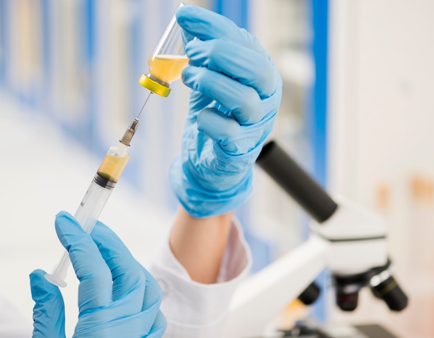 Scientist with surgical gloves filling up syringe