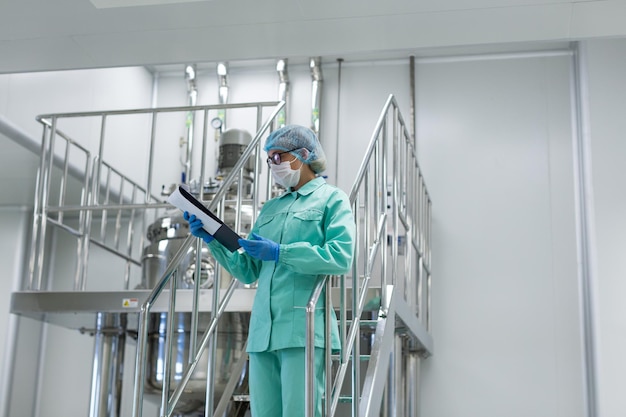 Scientist woman in blue suit looking in tablet standing on stairs