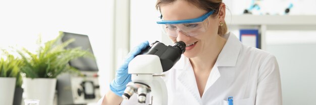 Scientist woman working on microscope and analyzing honeycomb of fruits microbiologist working