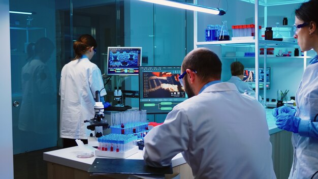 Scientists coworkers working in chemical modern equipped laboratory at night analysing test results