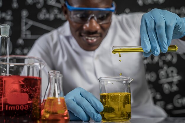 과학자들은 실험실에서 유리에 노란색 화학 물질을 떨어 뜨립니다.