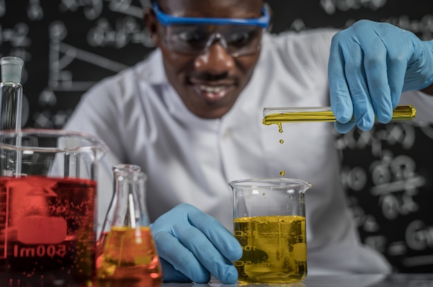 Ученые сбрасывают в стакан желтые химикаты в лаборатории