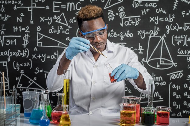 Foto gratuita gli scienziati rilasciano sostanze chimiche gialle e rosse nel bicchiere del laboratorio