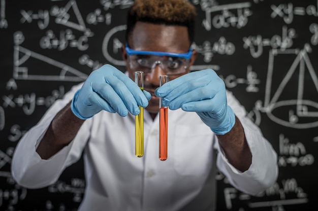 Foto gratuita gli scienziati esaminano i prodotti chimici arancioni e gialli in vetro in laboratorio