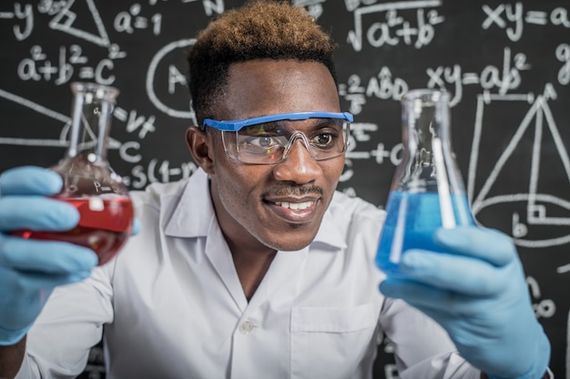Ученые смотрят на небесно-голубые химические вещества в стакане в лаборатории