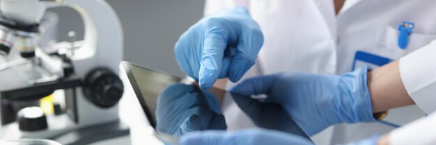 Scientists in sterile gloves hold tablet in laboratory digital applications for chemical