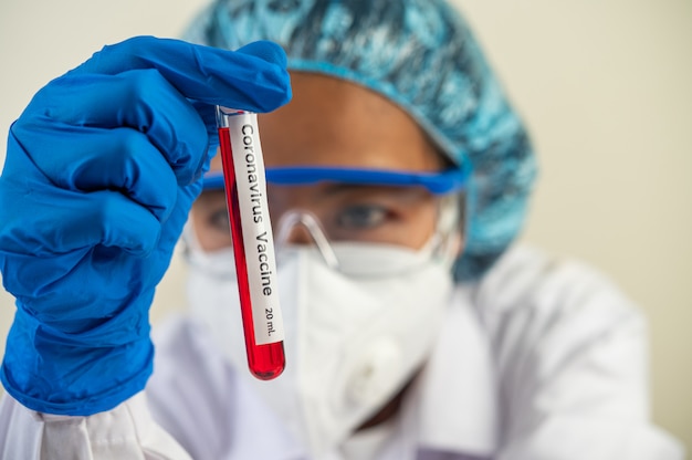 Scientists wear gloves and hold beakers.