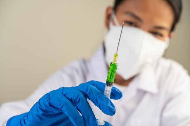 Scientists wearing masks and gloves Holding a syringe with a vaccine to prevent covid-19