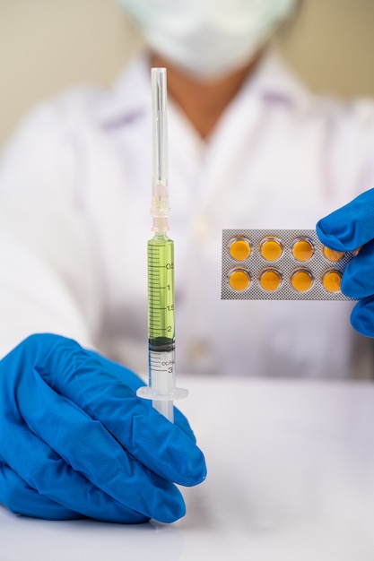 Free photo scientists wearing masks and gloves holding a syringe with a vaccine