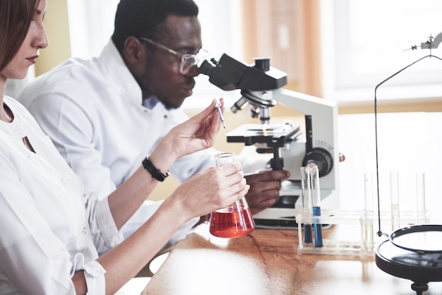 과학자들은 실험과 분석을 수행하여 실험실에서 현미경으로 긴밀하게 작업합니다.