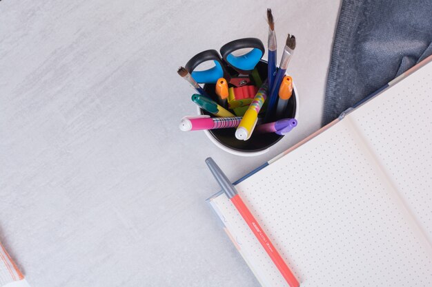 Scissors, brushes and pencils in pen holder and open copybook