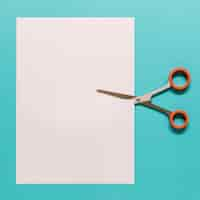 Free photo scissors cutting paper on blue background