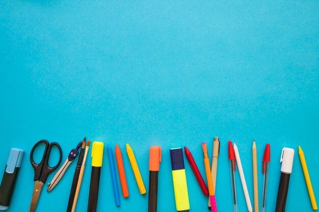 Scissors and writing supplies on blue background