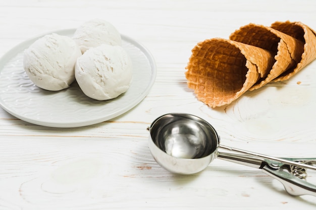 Scoop near plate with ice-cream and cones