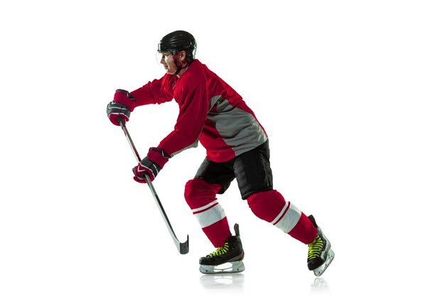 Забивая гол. Мужской хоккеист с клюшкой на ледовой площадке и белом фоне. Спортсмен в снаряжении и шлеме тренируется. Понятие спорта, здорового образа жизни, движения, движения, действий.
