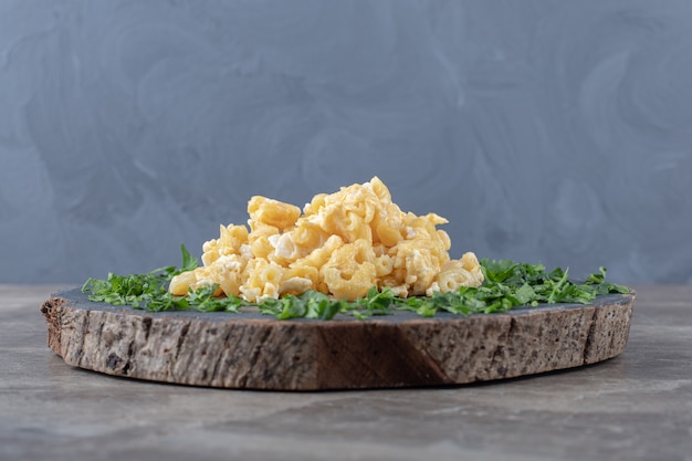 Scrambled eggs decorated with greens on wood piece.