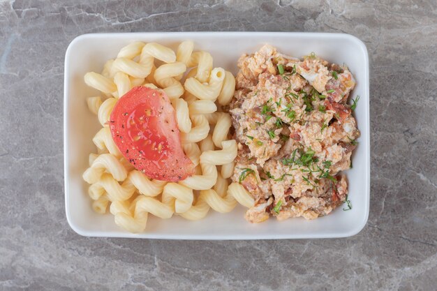 Scrambled eggs and pasta on white plate.