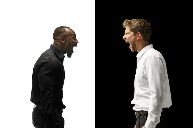 Free photo the screaming afro and caucasian men. mixed couple. dynamic image of male models on white and black studio. human facial emotions concept.