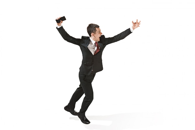Screaming businessman running with mobile phone over white studio