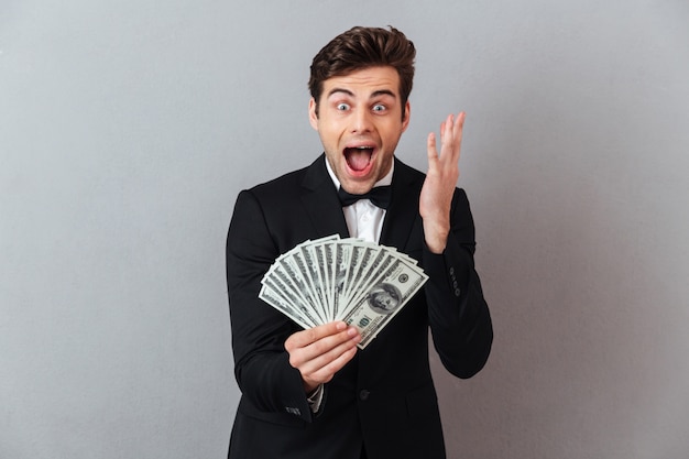 Screaming happy man in official suit holding money.