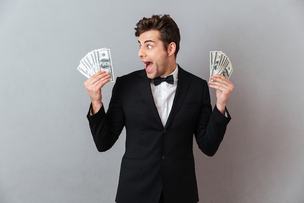 Screaming happy man in official suit holding money.