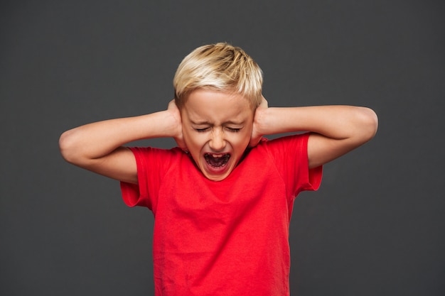 Free photo screaming little boy child covering ears with hands.