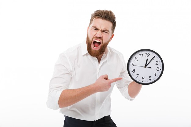 Screaming man in business clothes holding and pointing at clock